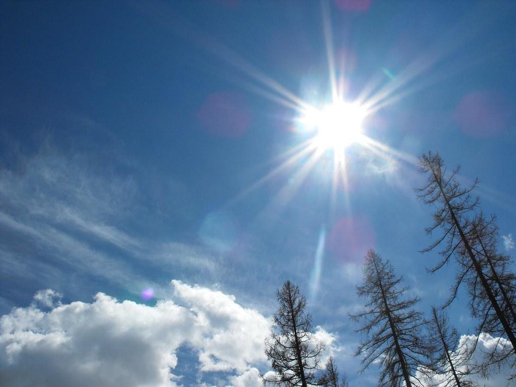 Sunce sja. Prikazuje se plavo nebo. Mogu se vidjeti drveće i oblaci.  